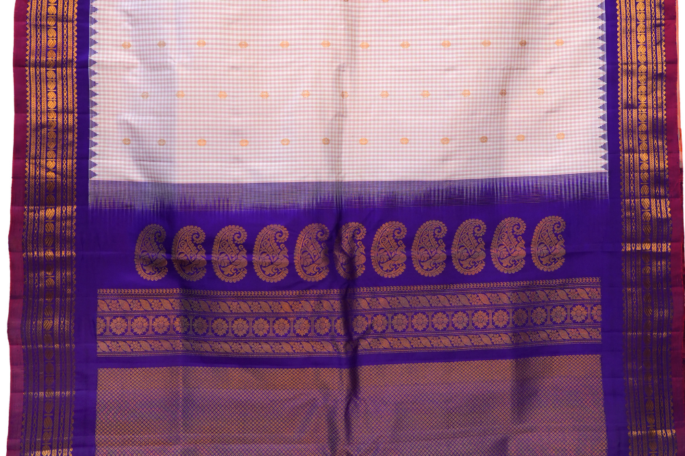 Traditional Gadwal silk saree featuring zari-woven borders and contrast blouse piece.
