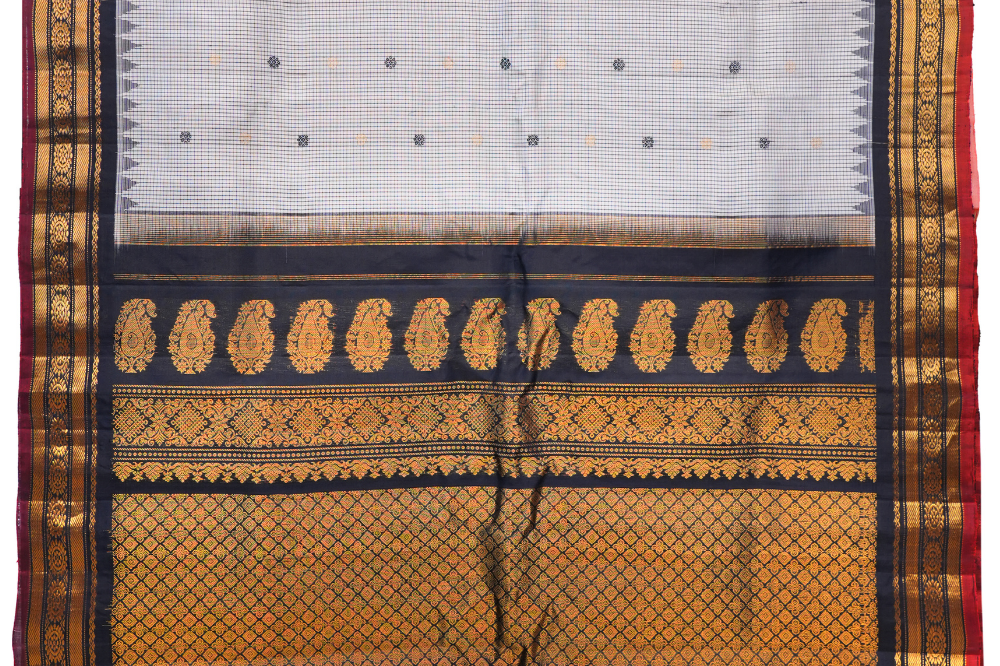 Traditional Gadwal silk saree featuring zari-woven borders and contrast blouse piece.
