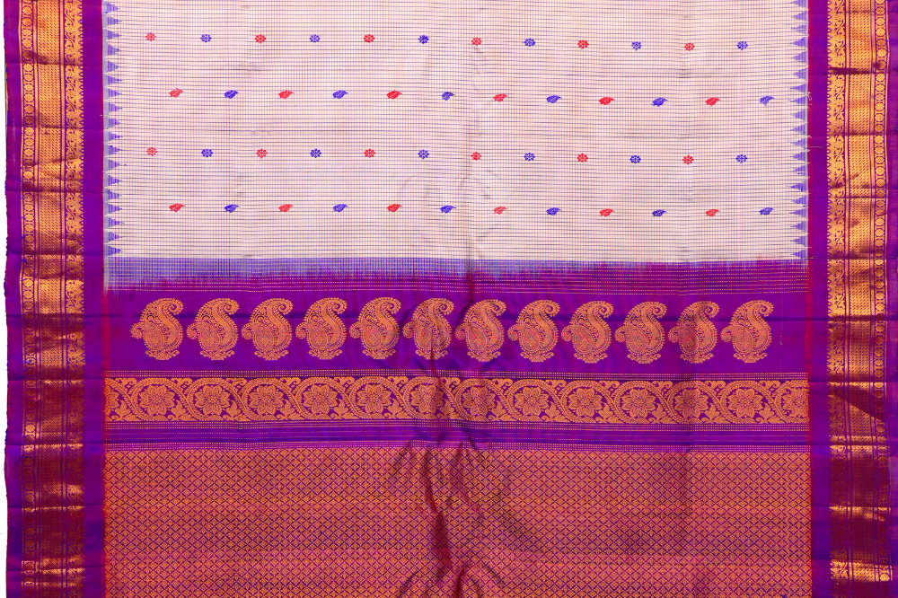 Traditional Gadwal silk saree featuring zari-woven borders and contrast blouse piece.
