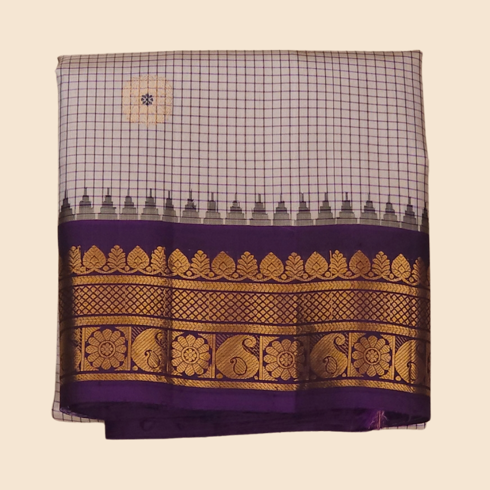 Traditional Gadwal silk saree featuring zari-woven borders and contrast blouse piece.
