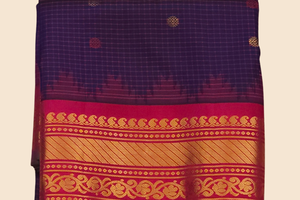 Traditional Gadwal silk saree featuring zari-woven borders and contrast blouse piece.
