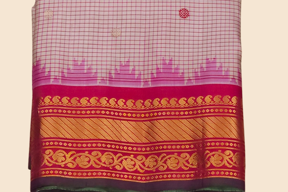Traditional Gadwal silk saree featuring zari-woven borders and contrast blouse piece.
