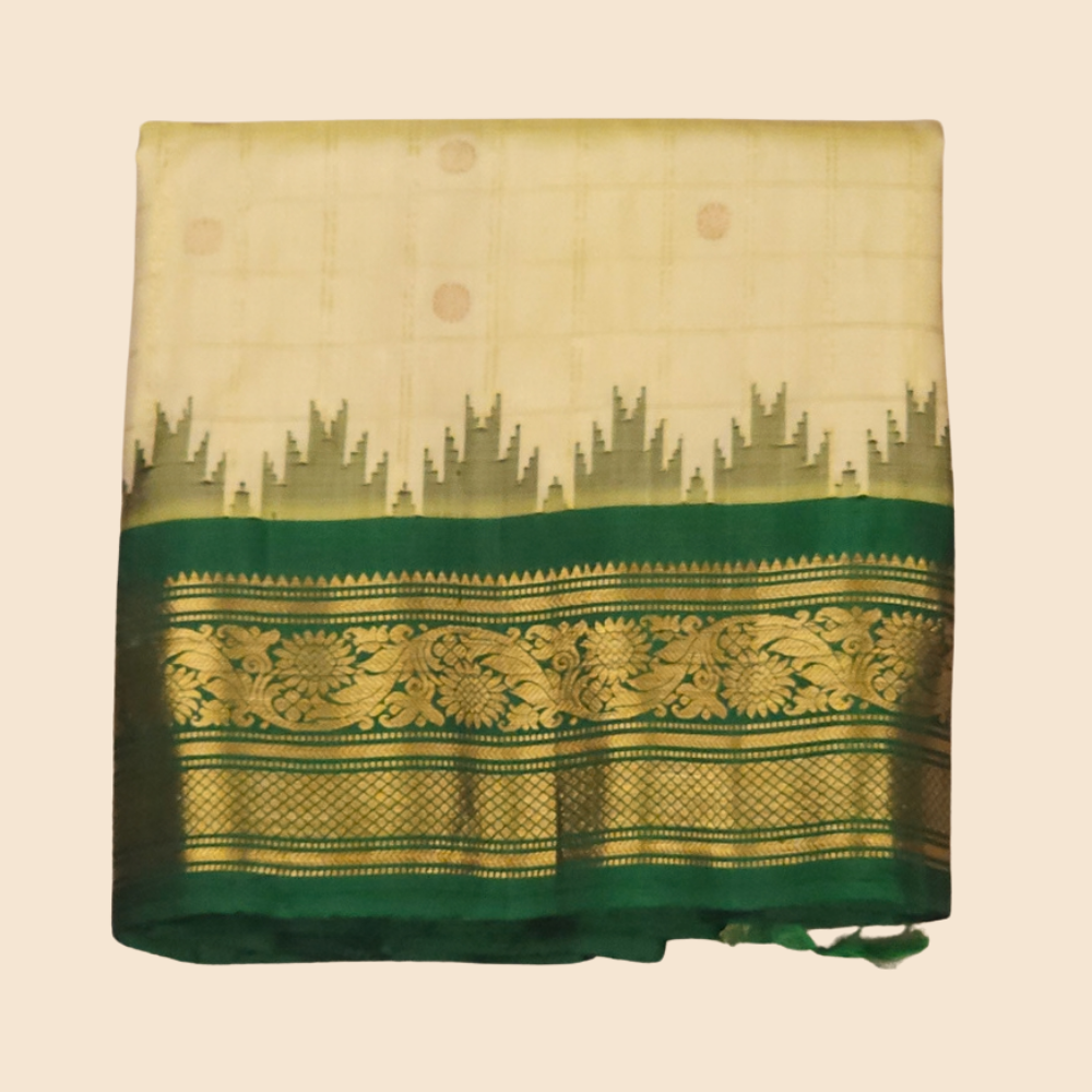Traditional Gadwal silk saree featuring zari-woven borders and contrast blouse piece.
