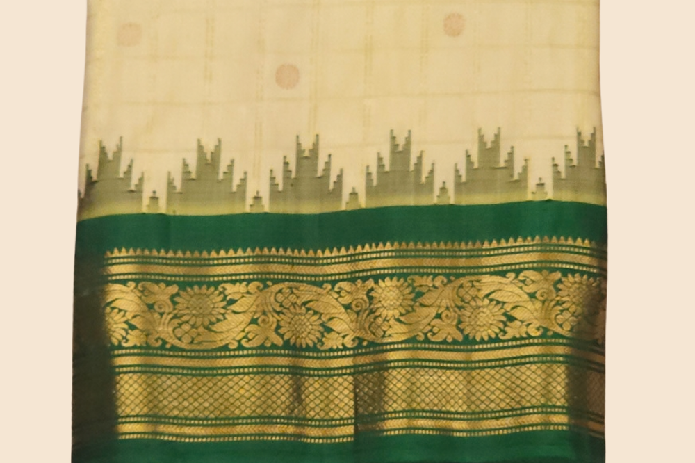 Traditional Gadwal silk saree featuring zari-woven borders and contrast blouse piece.
