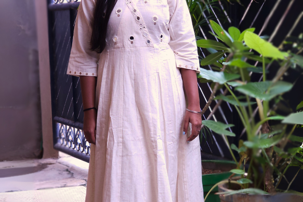 Woman in a white dress standing on a balcony with plants