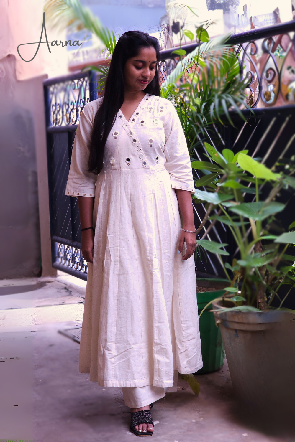 Woman in a white dress standing on a balcony with plants