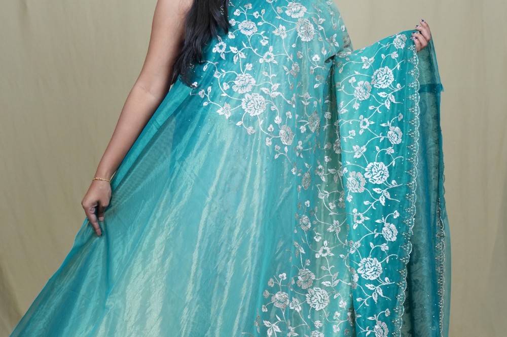Elegant ethnic tissue saree featuring cutwork borders and graceful running pallu design.
