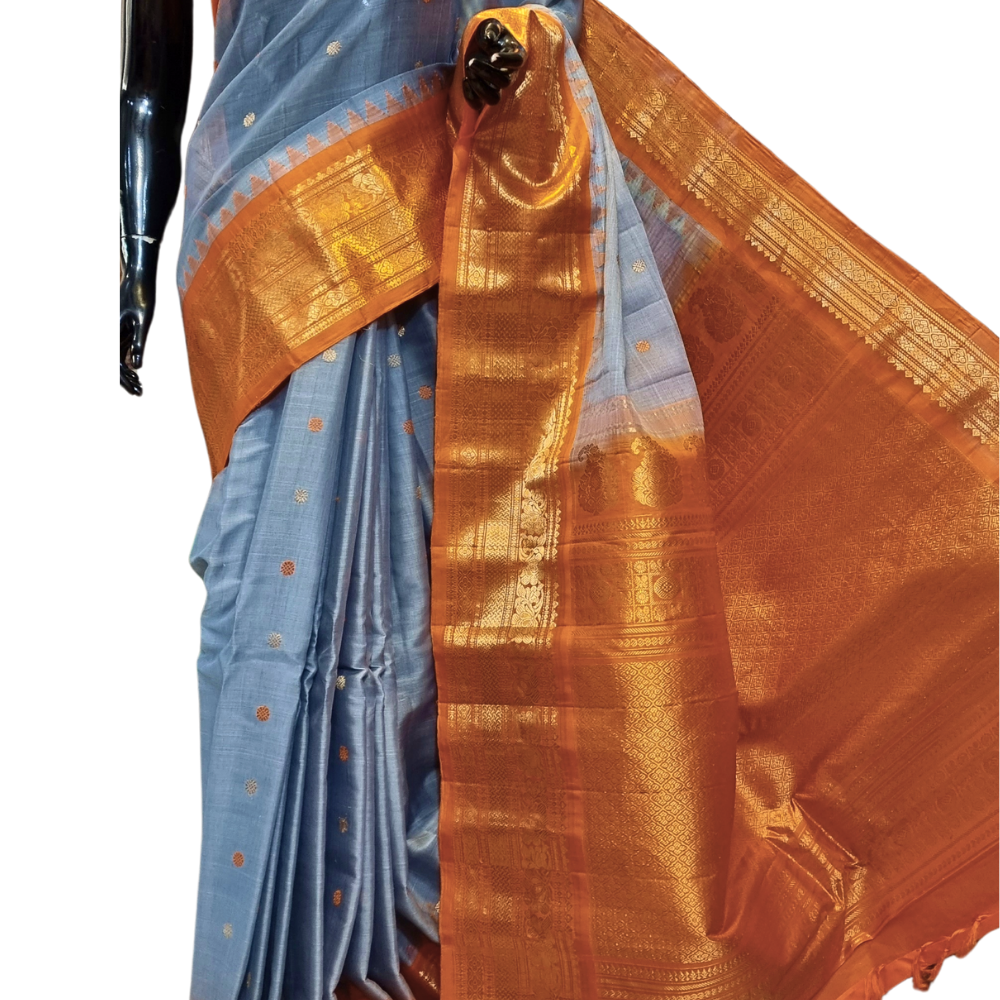 Handloom Gadwal silk cotton saree with all-over zari buttis and rich brocade pallu.
