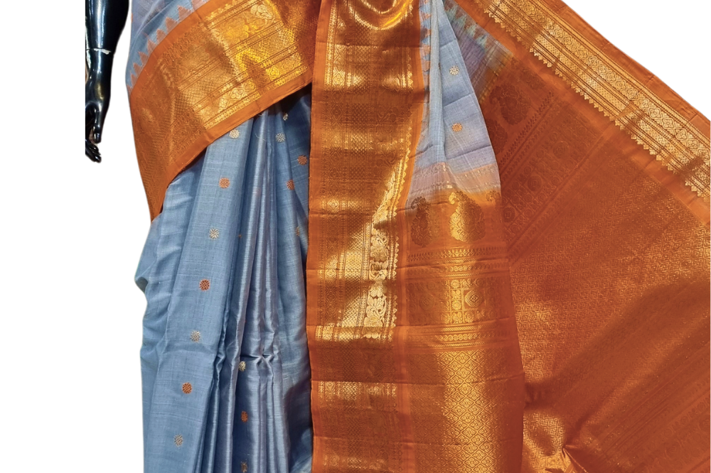Handloom Gadwal silk cotton saree with all-over zari buttis and rich brocade pallu.
