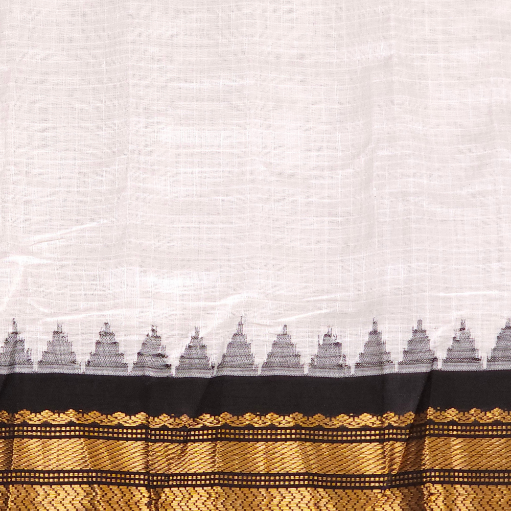 Half white and black handloom Gadwal saree draped, showing blouse piece and zari detailing