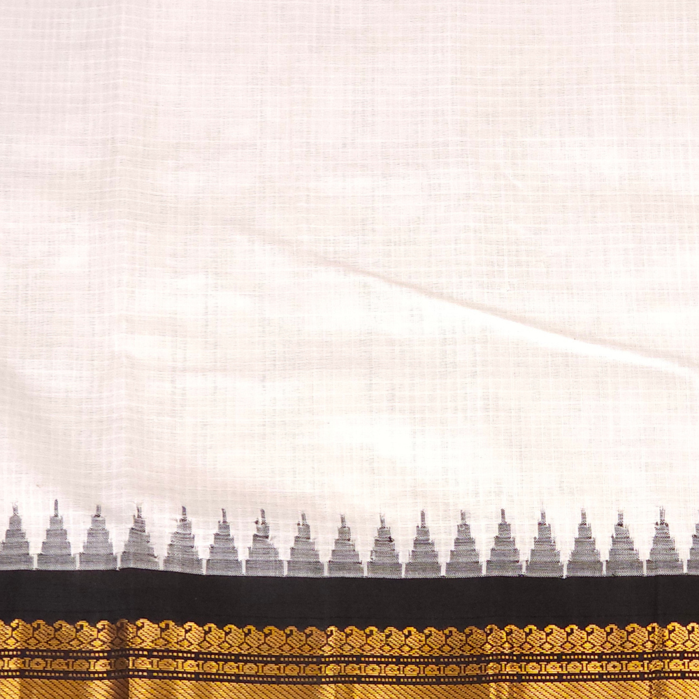 A close-up of a white or off-white fabric saree body with a black border and ornate gold zari embroidery, featuring a repeating small motif along the edge. A logo for 'Princess Lakshmi Silks' is visible in the top right corner.