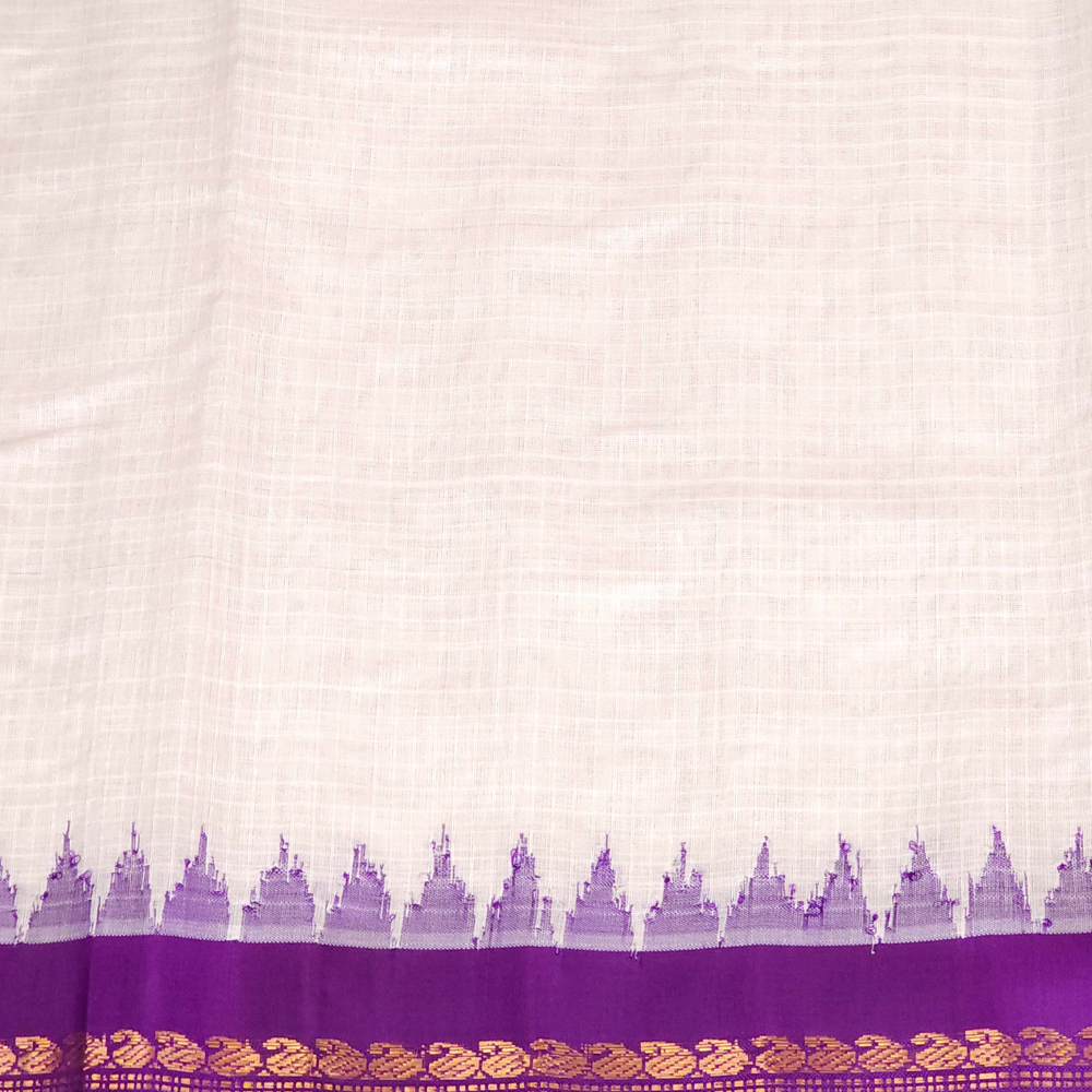 A close-up of a white or off-white silk fabric, likely a saree, featuring a purple border with a repeating motif and a wide gold zari woven pattern at the bottom. The brand logo 'Princess Lokhand Silk' is visible in the top right corner.