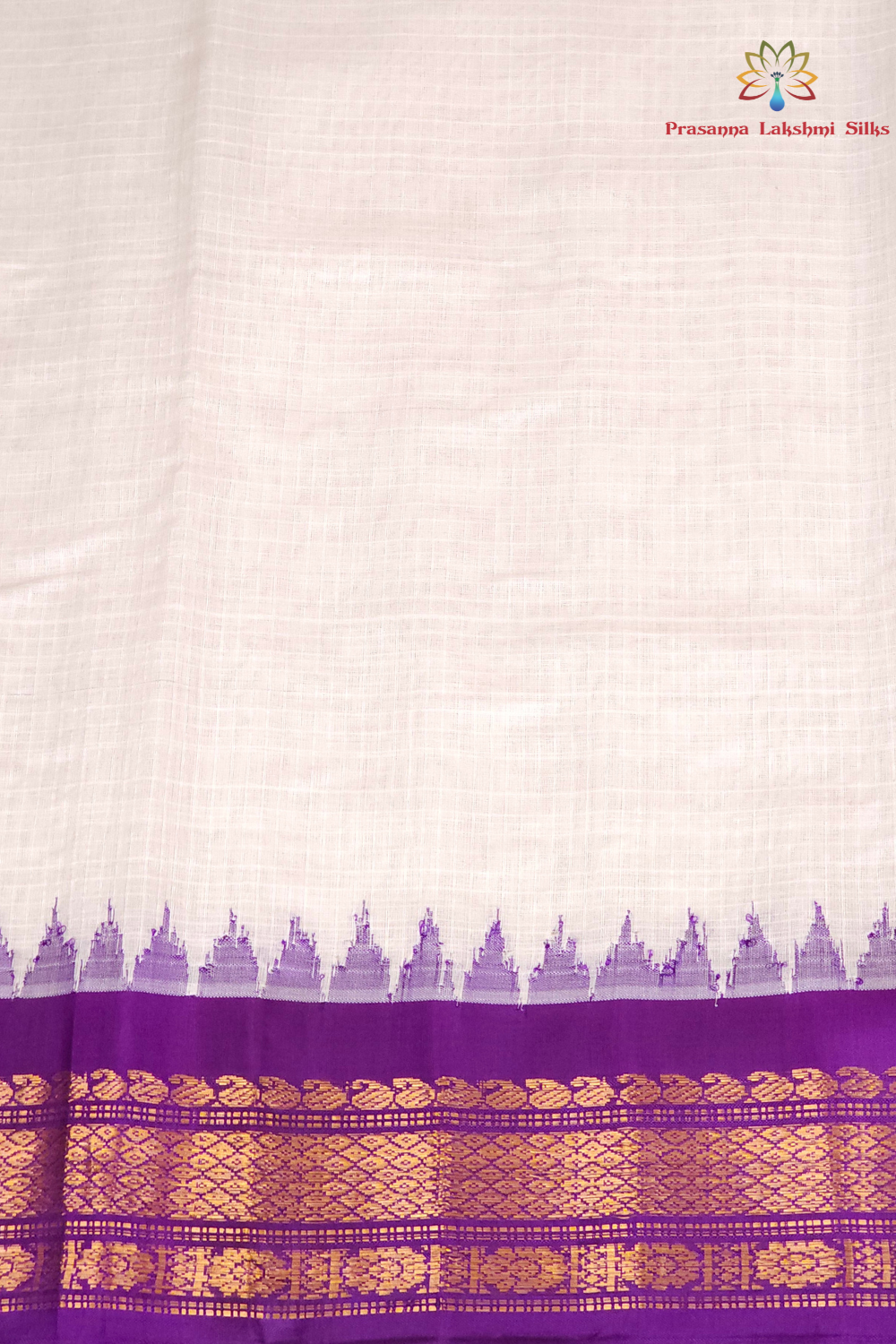 A close-up of a white or off-white silk fabric, likely a saree, featuring a purple border with a repeating motif and a wide gold zari woven pattern at the bottom. The brand logo 'Princess Lokhand Silk' is visible in the top right corner.